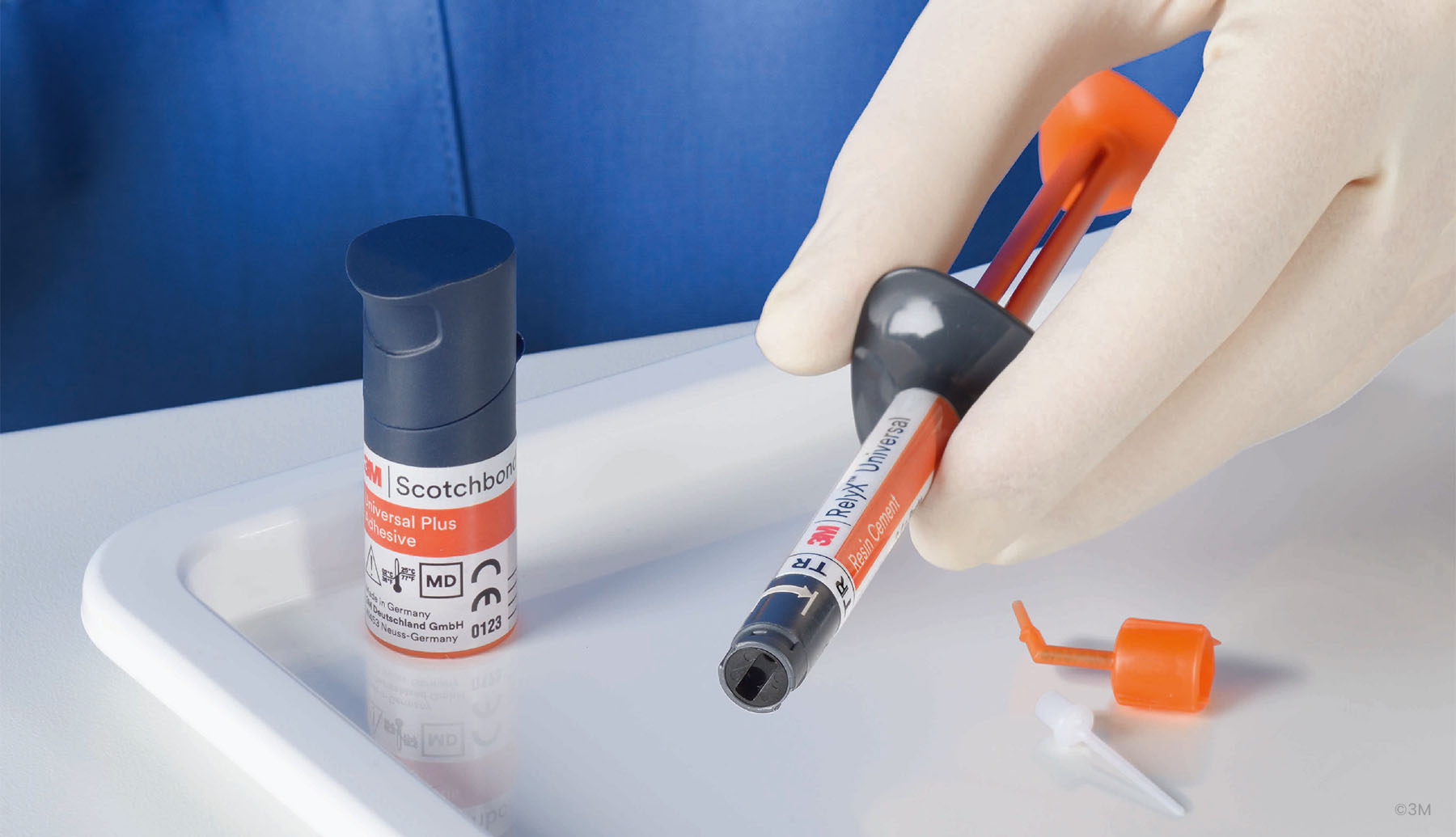 Hand holding the 3M RelyX Syringe showing the superior ergonomics next to a 3M Scotchbond bottle
