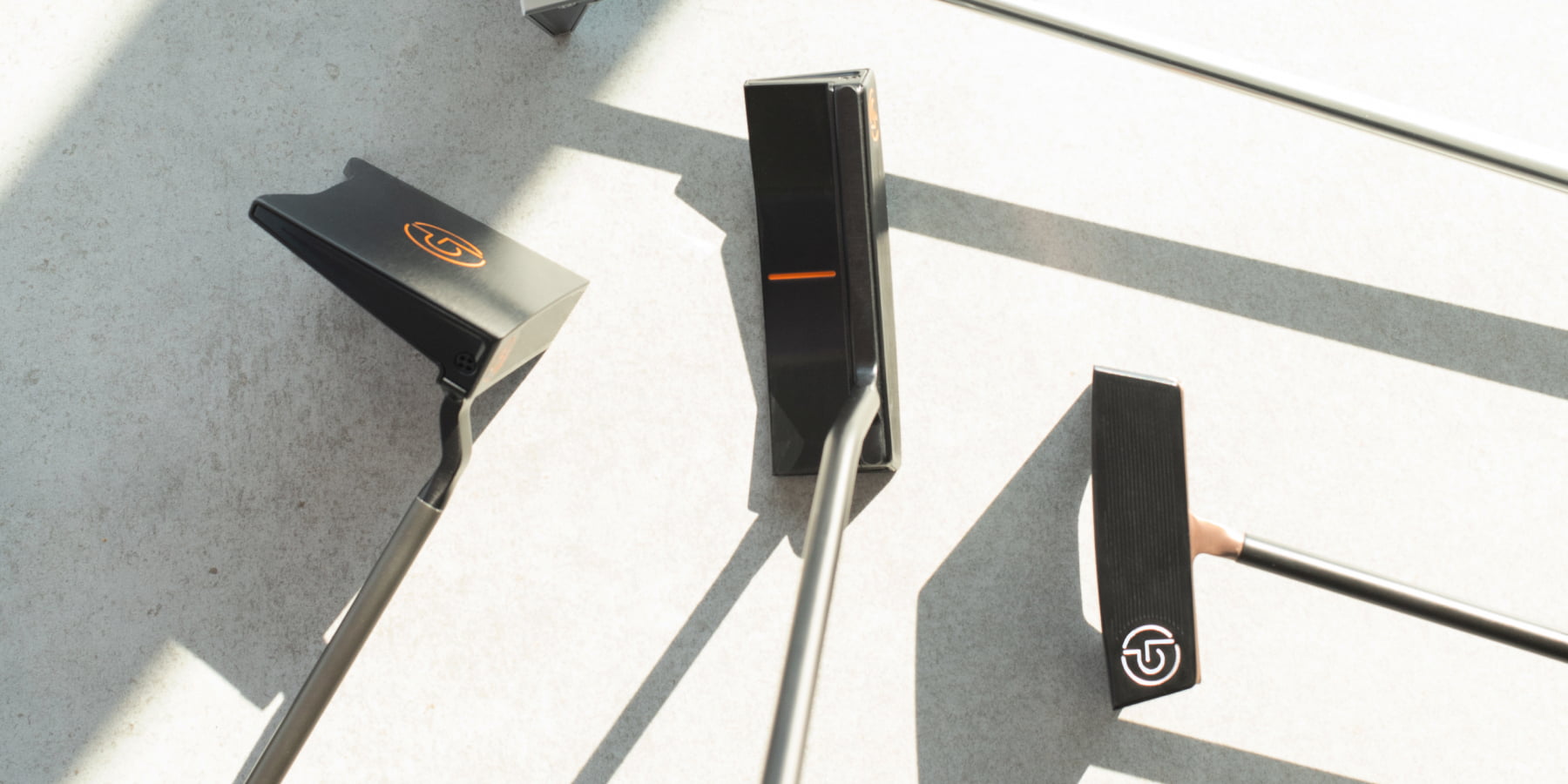 Three Lübbering Petersen GROOVIN' Putter in black with orange details from different views